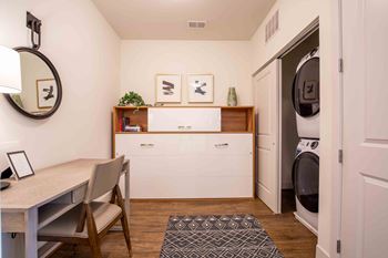 a laundry room with a table and chairs and a washing machine at Woodmore Grand Apartments in Bowie, MD 20721